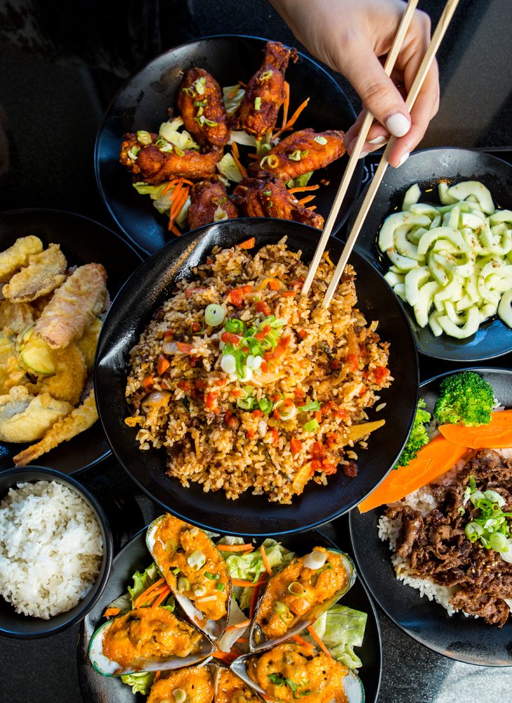 Fried rice surrounded by plates of appetizers including: Shrimp and Veggie Tempura, Sea Cucumber Salad, Asian Garlic Wings, Baked Green Muscles and Beef Teriyaki.